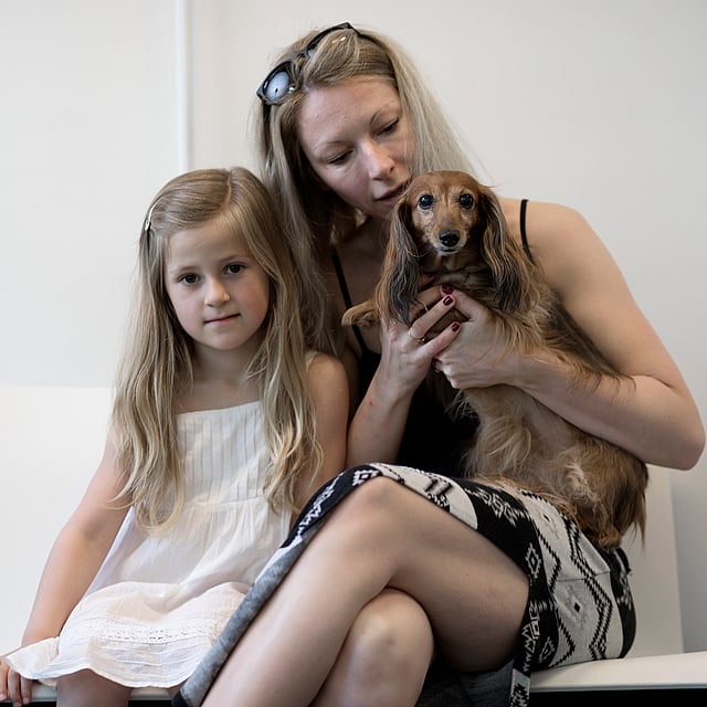 En person og et barn som holder en hund.