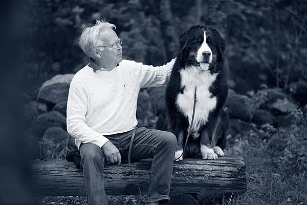 En person som sitter på en tømmerstokk med en hund.
