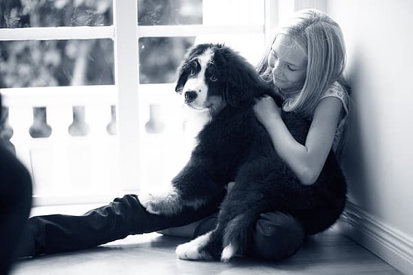 Et barn som sitter på gulvet med en hund.