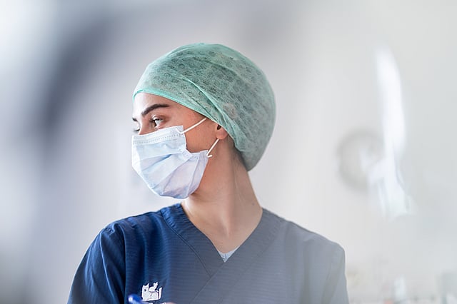 En person som har på seg en kirurgisk maske og skrubber.
